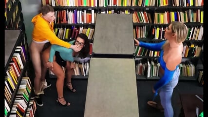A brunette with glasses gave a cap to a student in the library